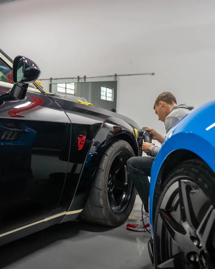 Technician polishing the fender of a black Dodge Demon with a dual-action polisher