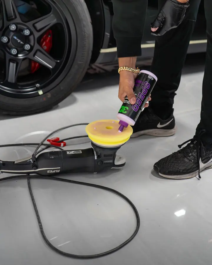 Polish being poured onto a yellow foam pad on a dual-action polisher