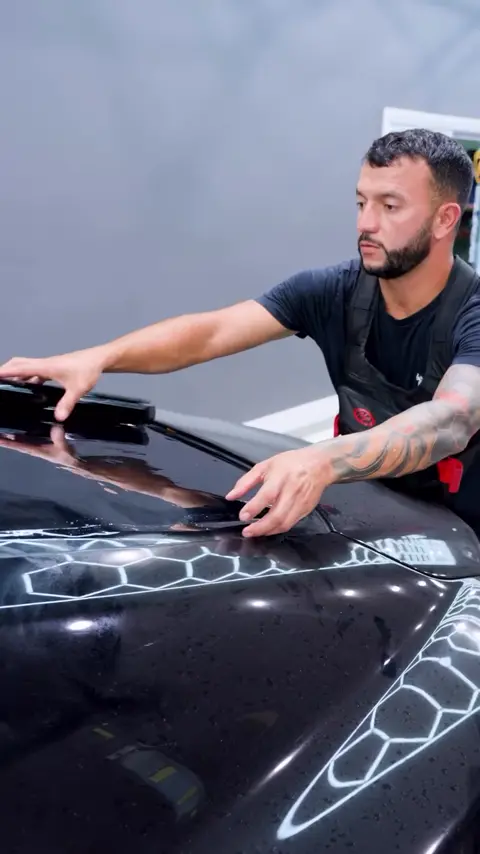 Technicians installing window tint on a black Rolls-Royce