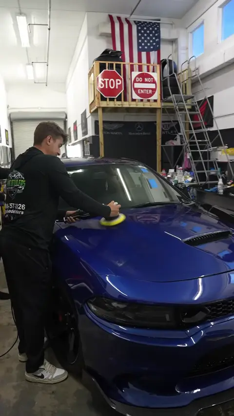 Technicians masking and machine polishing a Dodge Charger while explaining paint correction