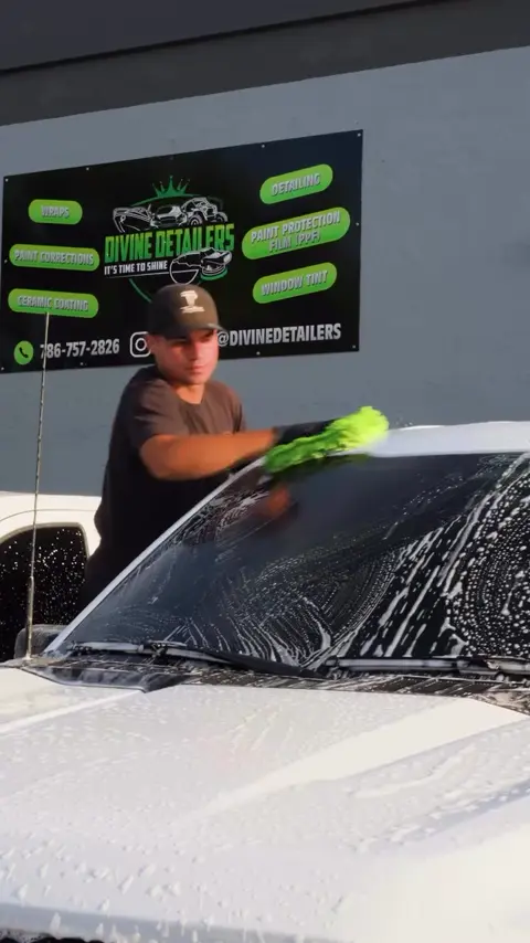 Technicians installing paint protection film and black trim wrap on a white Ford F-150