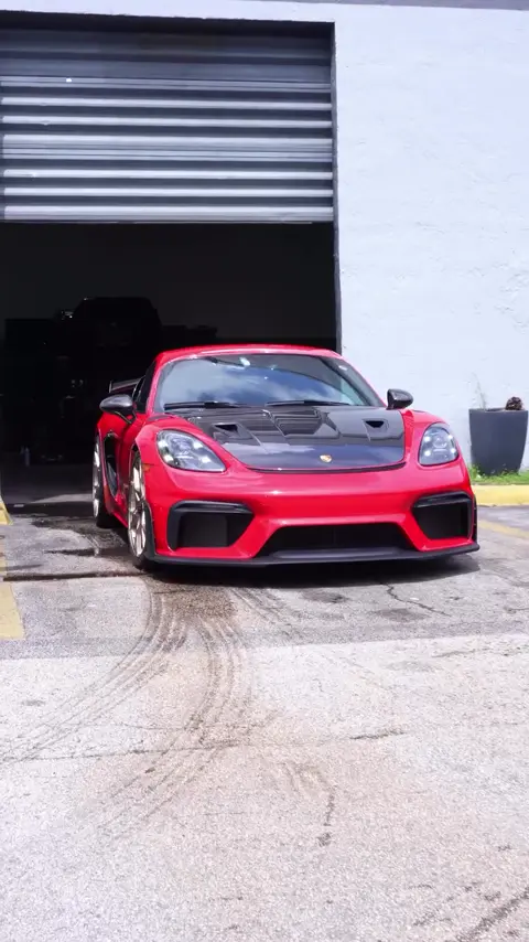 Technicians installing paint protection film on a red Porsche 718 GT4