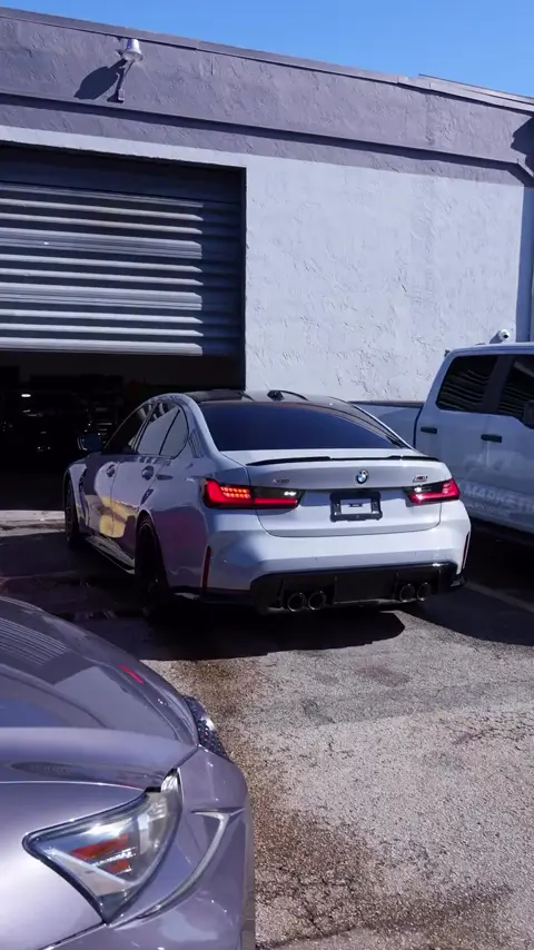 Technicians washing and applying ceramic coating to a gray BMW M3
