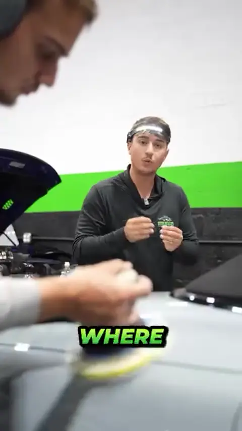 Technician machine polishing a gray car while explaining paint correction