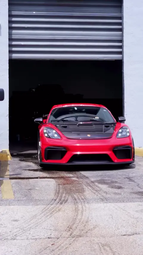 Technician tinting the windows of a red Porsche 718 GT4