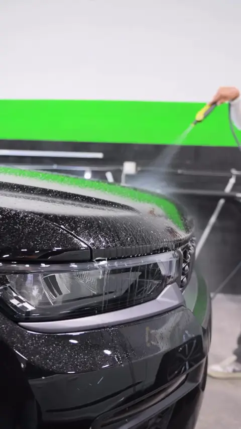 Technician installing clear paint protection film on the front end of a black Jeep