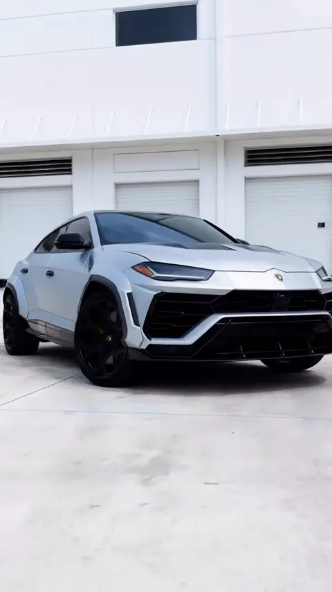 Technicians installing a satin silver wrap on a Lamborghini Urus